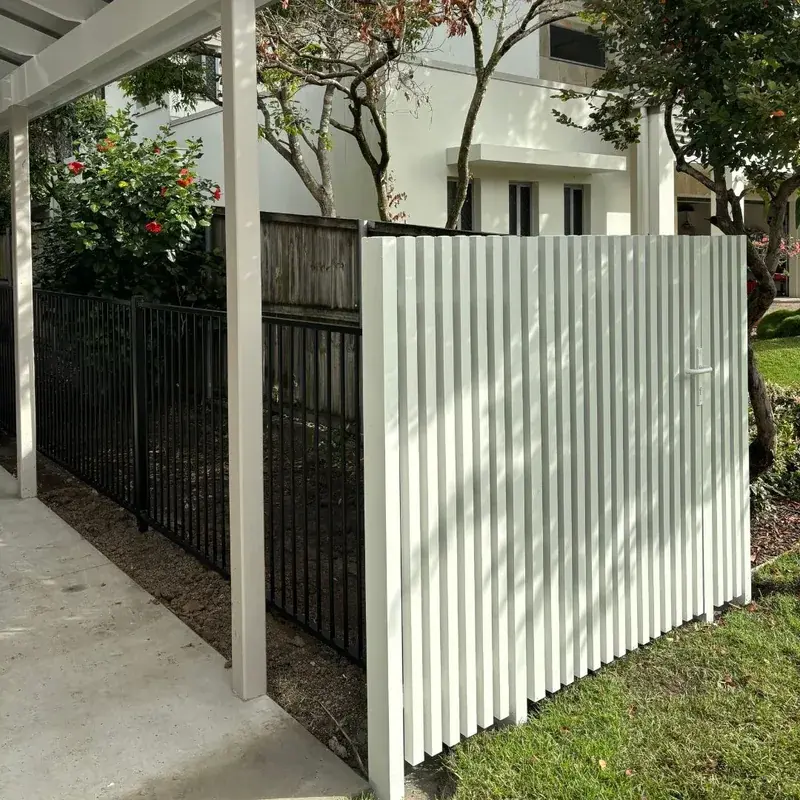 White vertical batten fence and gate beside a black tubular fence